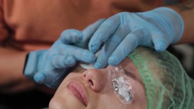 Kalıcı bir makyöz, bir kadının göz kapaklarına dövme yaptırır..