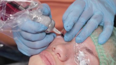 Kalıcı bir makyöz, bir kadının göz kapaklarına dövme yaptırır..