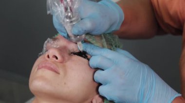 Kalıcı bir makyöz, bir kadının göz kapaklarına dövme yaptırır..