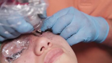 Kalıcı bir makyöz, bir kadının göz kapaklarına dövme yaptırır..