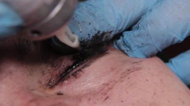 Kalıcı bir makyöz, bir kadının göz kapaklarına dövme yaptırır..