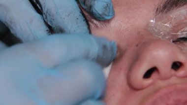 Kalıcı bir makyöz, bir kadının göz kapaklarına dövme yaptırır..