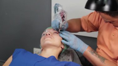 Kalıcı bir makyöz, bir kadının göz kapaklarına dövme yaptırır..