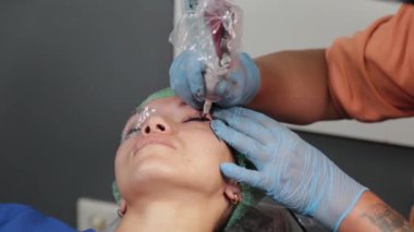 Kalıcı bir makyöz, bir kadının göz kapaklarına dövme yaptırır..