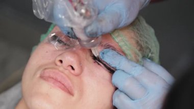 Kalıcı bir makyöz, bir kadının göz kapaklarına dövme yaptırır..