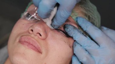 Kalıcı bir makyöz, bir kadının göz kapaklarına dövme yaptırır..