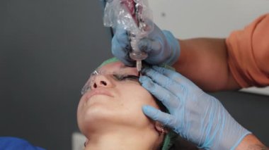 Kalıcı bir makyöz, bir kadının göz kapaklarına dövme yaptırır..