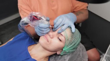 Kalıcı bir makyöz, bir kadının göz kapaklarına dövme yaptırır..