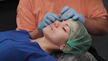 Kalıcı bir makyöz, bir kadının göz kapaklarına dövme yaptırır..