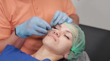 Kalıcı bir makyöz, bir kadının göz kapaklarına dövme yaptırır..