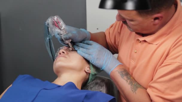 Trvalý maskér dostane tetování na ženských horních víčkách. — Stock video