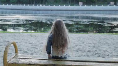 Nehrin kıyısındaki bankta oturan güzel kız.