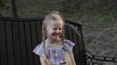 Parktaki bankta gülümseyen güzel mutlu küçük kız..