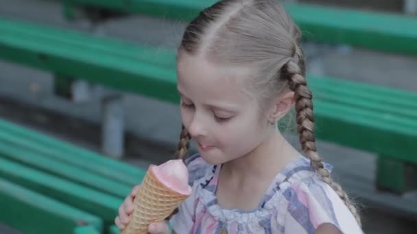 Piękna szczęśliwa dziewczyna jedząca lody w parku na ławce. — Wideo stockowe