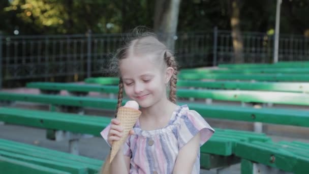 Schöne glückliche Mädchen essen Eis im Park auf einer Bank.