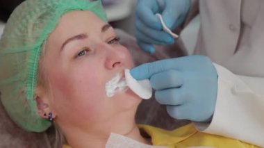 Doktor kozmetik uzmanı kadına dudak büyütme ameliyatı yapıyor..