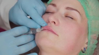Doktor kozmetik uzmanı kadına dudak büyütme ameliyatı yapıyor..