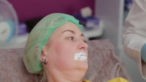Красивая женщина с анестезирующим гелем на губах перед процедурой наращивания губ. — стоковое видео