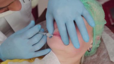 Doktor kozmetik uzmanı kadına dudak büyütme ameliyatı yapıyor..