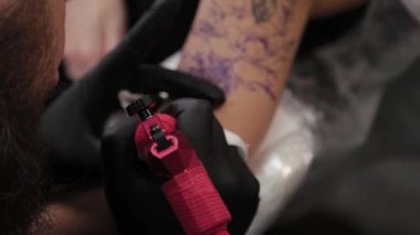 Dövme sanatçısı genç bir kızın kolunda dövme yapıyor..