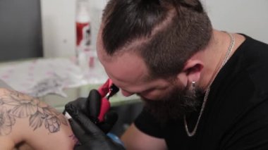 Dövme sanatçısı genç bir kızın kolunda dövme yapıyor..