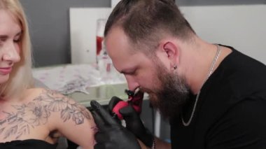 Dövme sanatçısı genç bir kızın kolunda dövme yapıyor..