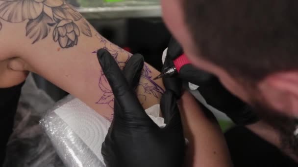 Tattoo artiste fait un tatouage sur un bras de jeunes filles. — Video