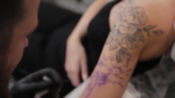 Tatuagem artista faz uma tatuagem em um braço de meninas jovens. — Vídeo de Stock