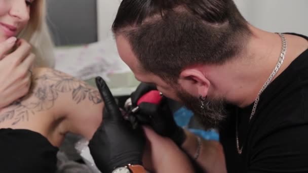 Tattoo artist makes a tattoo on a young girls arm. — Stock Video