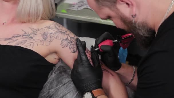 Tattoo artist makes a tattoo on a young girls arm. — Stock Video