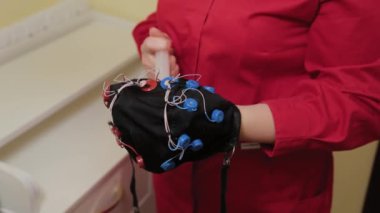 Doktorun ofisinde beyin EEG analizi için hazırlanıyorum. Bir kızın elektroensefalografik muayenesi için bir aygıt kurulumu.