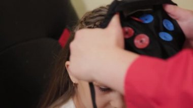 Doktorun ofisinde beyin EEG analizi için hazırlanıyorum. Bir kızın elektroensefalografik muayenesi için bir aygıt kurulumu.