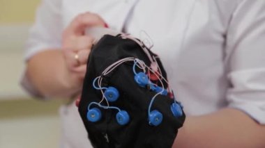 Doktorun ofisinde beyin EEG analizi için hazırlanıyorum. Bir kızın elektroensefalografik muayenesi için bir aygıt kurulumu.