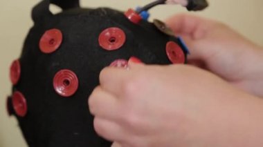 Doktorun ofisinde beyin EEG analizi için hazırlanıyorum. Bir kızın elektroensefalografik muayenesi için bir aygıt kurulumu.