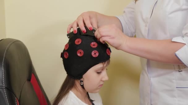 Préparation d'une analyse EEG du cerveau dans le bureau des médecins. Installation d'un dispositif d'examen électroencéphalographique d'une fille. — Video