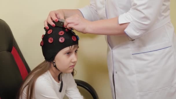 Przygotowuję się do analizy EEG mózgu w gabinecie lekarskim. Instalacja urządzenia do badania elektroencefalograficznego dziewczynki. — Wideo stockowe