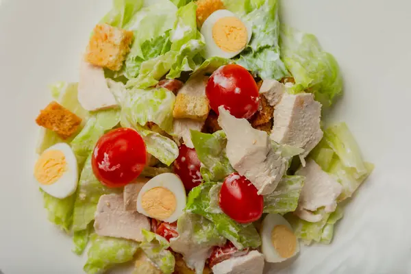 Свіжий салат з Цезаря в білій тарілці на столі . — стокове фото