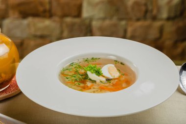 Taze sebzeli çorba, et ve yumurta beyaz tabakta..