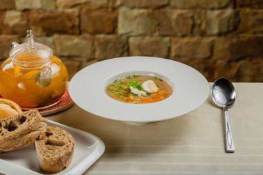 Taze sebzeli çorba, et ve yumurta beyaz tabakta..