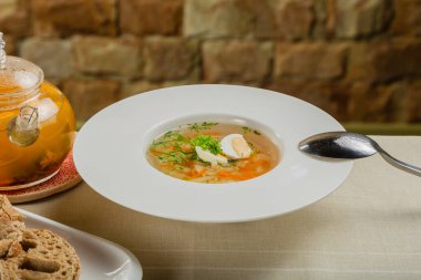 Taze sebzeli çorba, et ve yumurta beyaz tabakta..