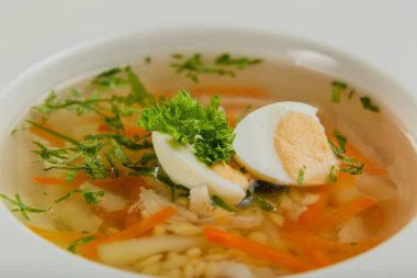 Taze sebzeli çorba, et ve yumurta beyaz tabakta..