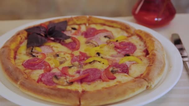 Świeża pizza z kiełbasą i serem na białym talerzu. — Wideo stockowe