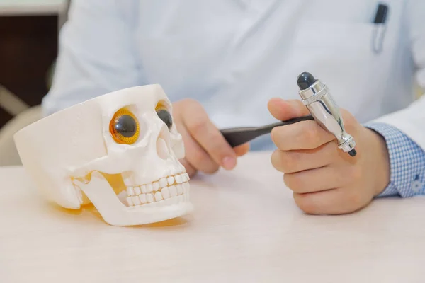 Médico varón con un cráneo y un martillo en las manos en la mesa. — Foto de Stock