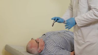 Erkek doktor nörolog yaşlı bir hastayı muayene ediyor..