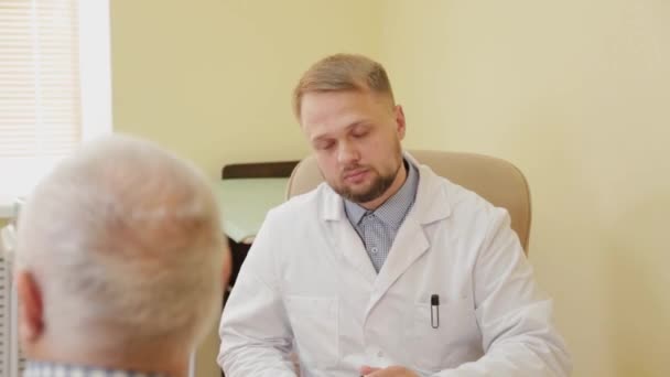 Männlicher Arzt im Gespräch mit einem älteren Patienten. — Stockvideo