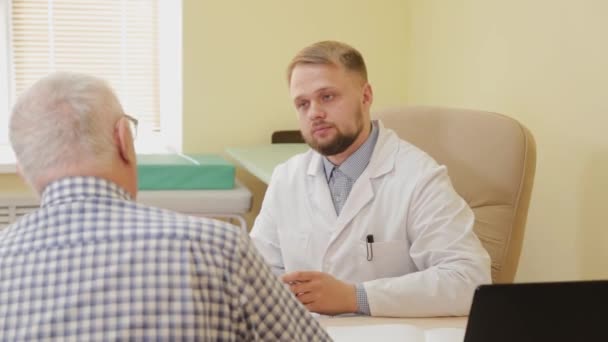 Dokter laki-laki berbicara dengan pasien tua. — Stok Video
