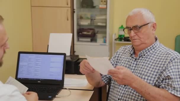 Neurólogo masculino prescribe una prescripción para un paciente anciano. — Vídeos de Stock