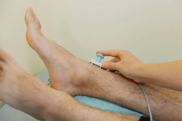 Kvinnlig läkare sätter en sensor på patientens ben. — Stockfoto