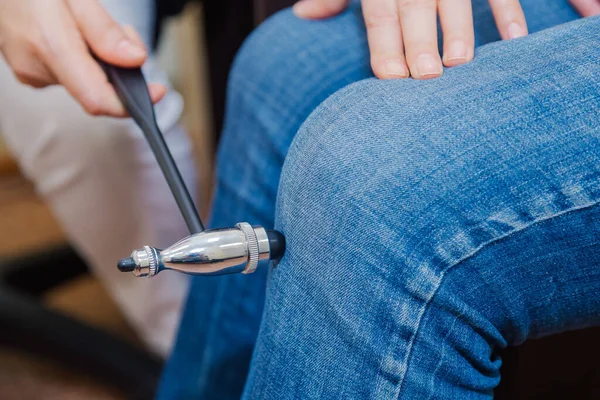 Woman neurologist examines a patient with a hammer in a private clinic