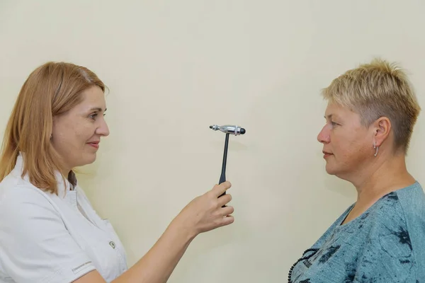 Žena neurologka vyšetřuje pacienta kladivem na soukromé klinice — Stock fotografie